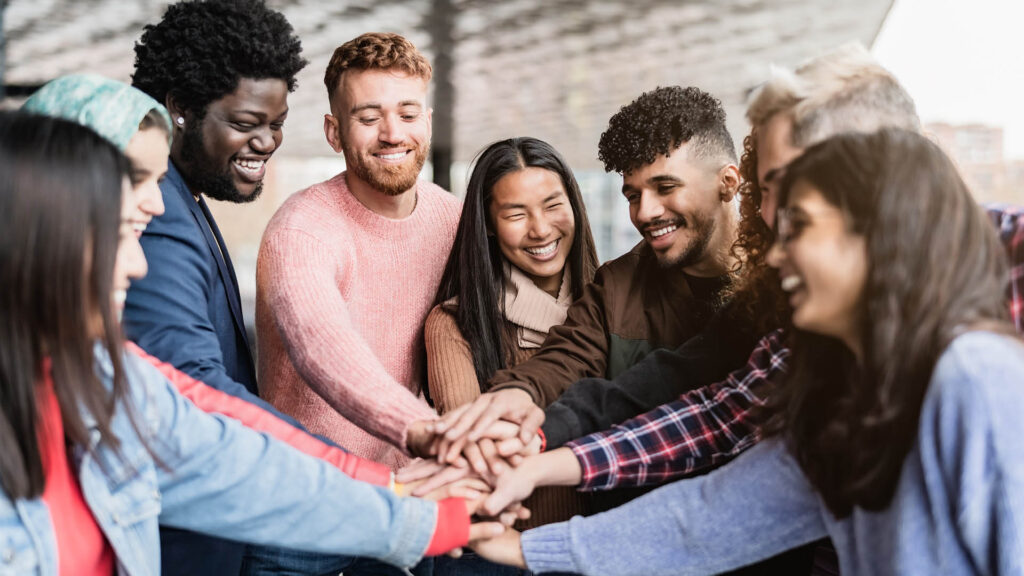 Young multiracial friends stacking hands together outdoor